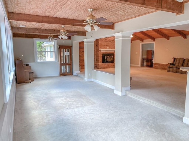 unfurnished living room featuring ceiling fan, wooden ceiling, a brick fireplace, decorative columns, and light colored carpet