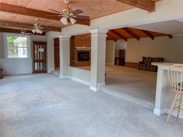 unfurnished living room featuring light carpet, decorative columns, a brick fireplace, and wood ceiling