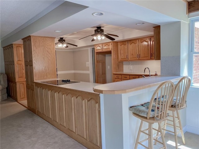 kitchen featuring plenty of natural light, black electric cooktop, kitchen peninsula, and a breakfast bar area