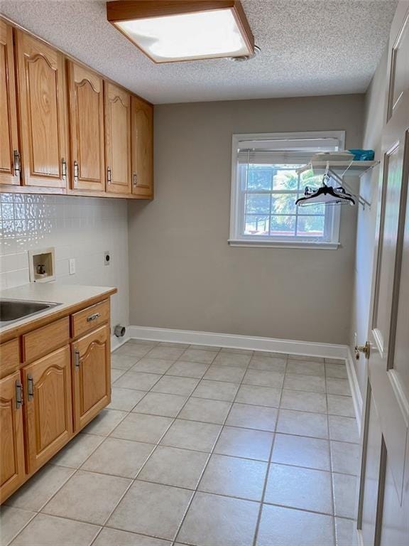 laundry room featuring cabinets, hookup for a washing machine, a textured ceiling, electric dryer hookup, and light tile patterned floors