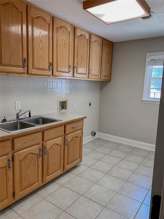 kitchen featuring decorative backsplash, sink, light tile patterned floors, and a textured ceiling