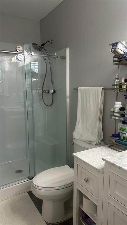 bathroom featuring toilet, vanity, and a shower with shower door