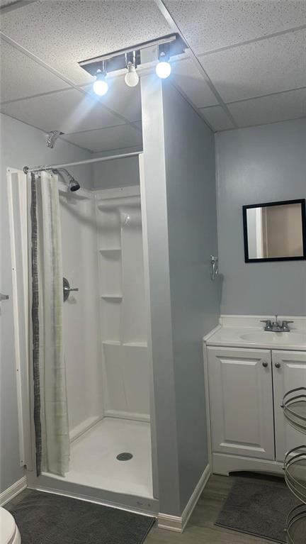 bathroom with hardwood / wood-style flooring, sink, a drop ceiling, and a shower with shower curtain