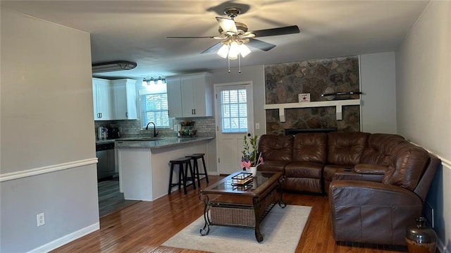 living room with ceiling fan, sink, a fireplace, and dark hardwood / wood-style flooring