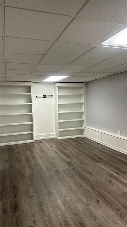 interior space featuring a paneled ceiling, built in features, and dark hardwood / wood-style floors