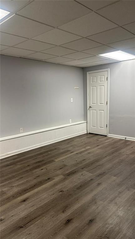 spare room featuring a drop ceiling and dark wood-type flooring