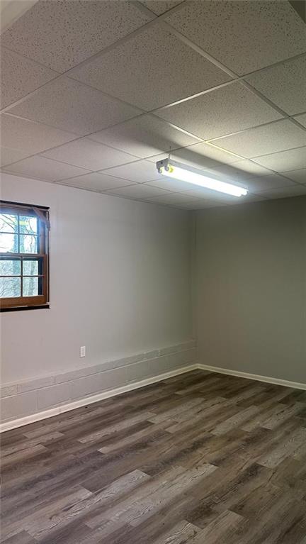 unfurnished room featuring dark hardwood / wood-style floors and a paneled ceiling