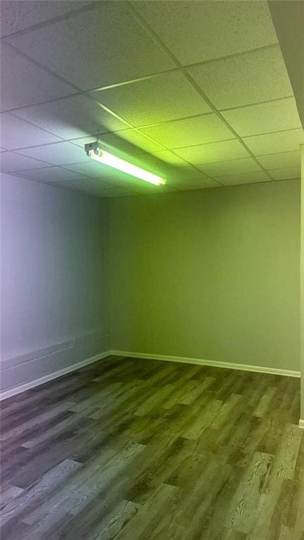 empty room with a drop ceiling and wood-type flooring