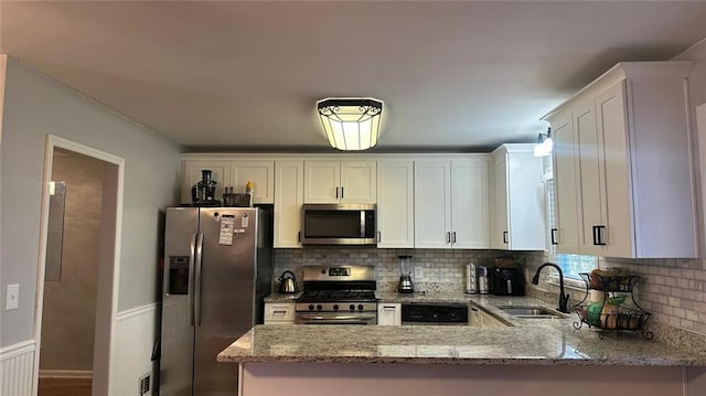 kitchen with white cabinetry, sink, stainless steel appliances, and kitchen peninsula