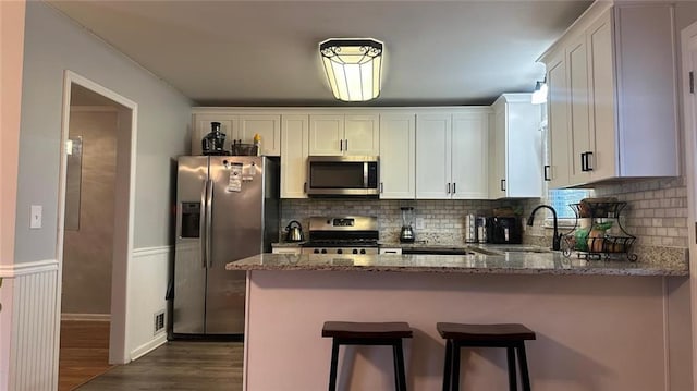 kitchen featuring appliances with stainless steel finishes, stone countertops, white cabinetry, sink, and dark wood-type flooring