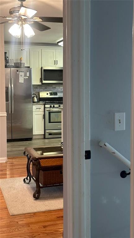 kitchen with hardwood / wood-style flooring, ceiling fan, stainless steel appliances, and white cabinetry