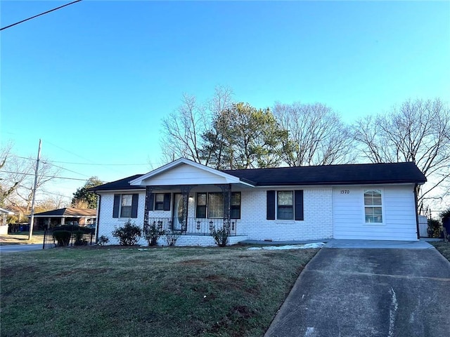 ranch-style house featuring a carport, covered porch, and a front yard