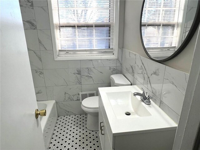 full bathroom with plenty of natural light, tile walls, toilet, and vanity