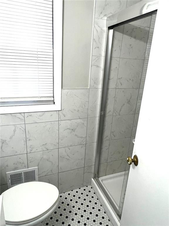 bathroom featuring toilet, tile patterned floors, and walk in shower