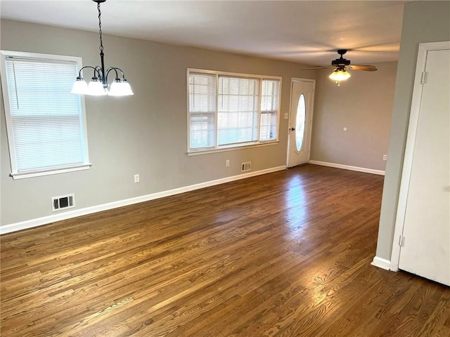 spare room with ceiling fan with notable chandelier and dark hardwood / wood-style flooring