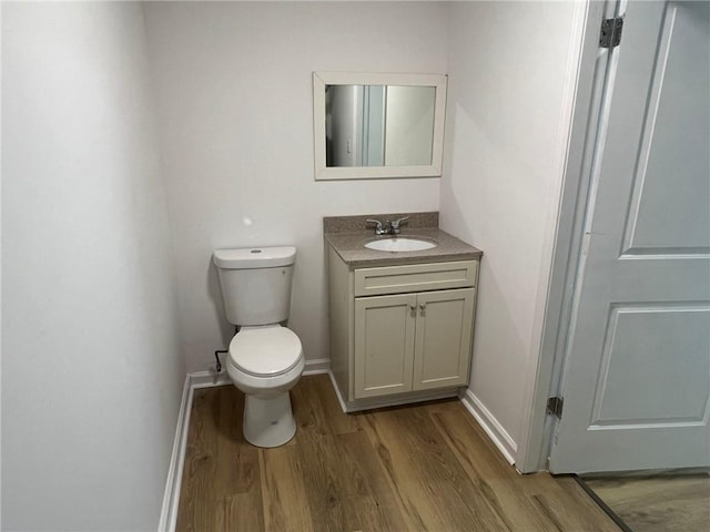 bathroom with toilet, wood-type flooring, and vanity