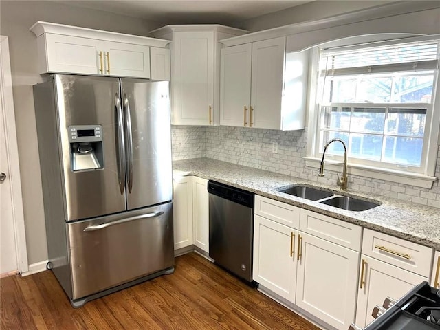 kitchen featuring white cabinetry, appliances with stainless steel finishes, backsplash, light stone countertops, and sink