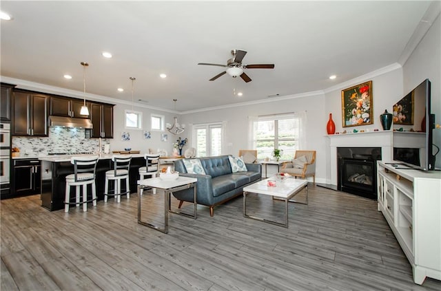 living room featuring ceiling fan, light wood-type flooring, and ornamental molding