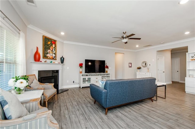 living room featuring ceiling fan, crown molding, and light hardwood / wood-style flooring