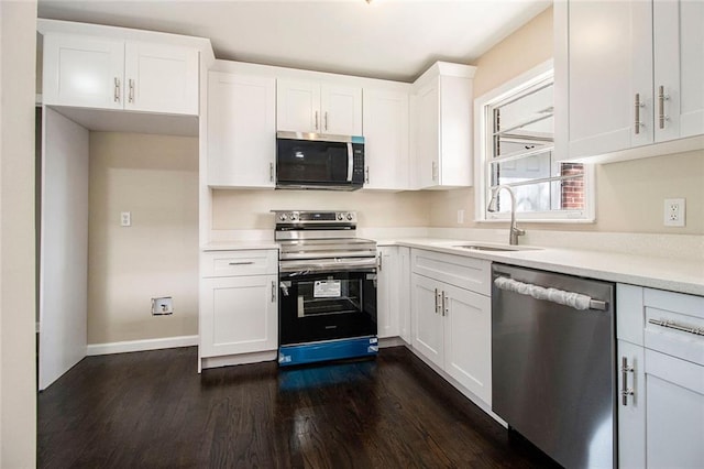 1207 Ellington Dr, Morrow, GA 30260 - kitchen with appliances with stainless steel finishes, a sink, dark wood-type flooring, white cabinets, and baseboards