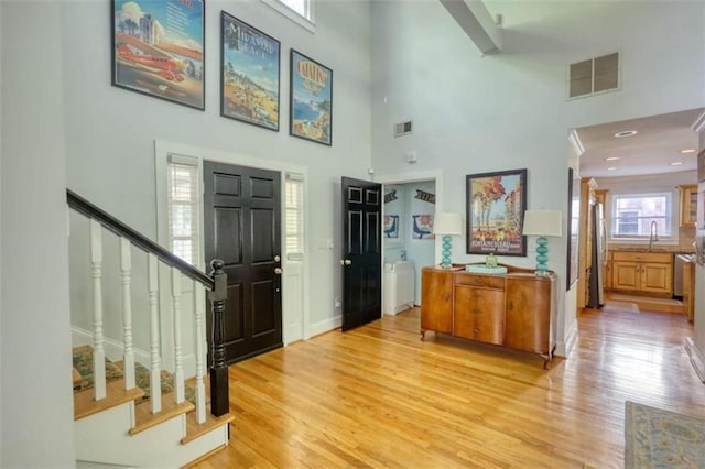 entrance foyer with a high ceiling, stairway, light wood finished floors, and baseboards