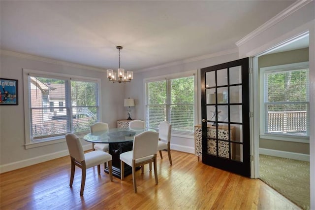 dining space featuring baseboards, a chandelier, light wood-style flooring, and ornamental molding