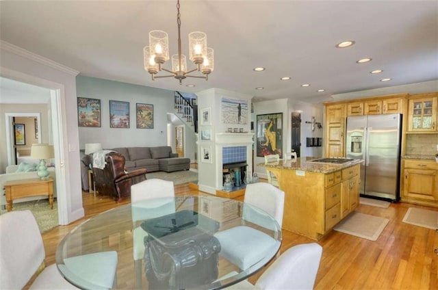 dining space featuring light wood-style floors, recessed lighting, a chandelier, ornamental molding, and stairs