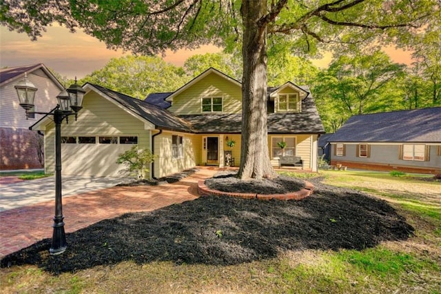 view of front of property featuring an attached garage, decorative driveway, and covered porch