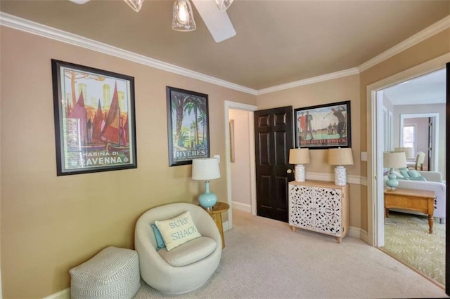 living area with carpet floors, ornamental molding, a ceiling fan, and baseboards