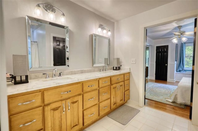 ensuite bathroom featuring a ceiling fan, double vanity, and tile patterned floors