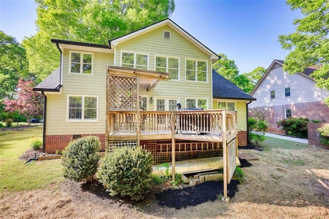 back of house with a deck, roof with shingles, and a yard