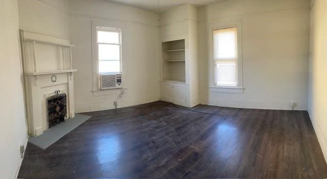 unfurnished living room with dark hardwood / wood-style floors, a healthy amount of sunlight, and cooling unit