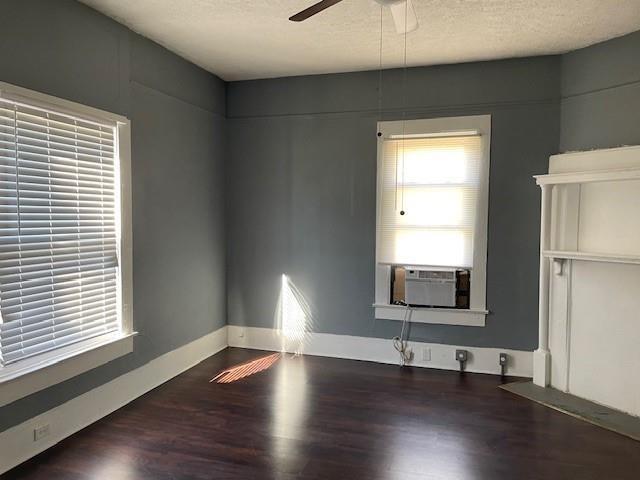 empty room featuring a textured ceiling, dark hardwood / wood-style floors, ceiling fan, and cooling unit