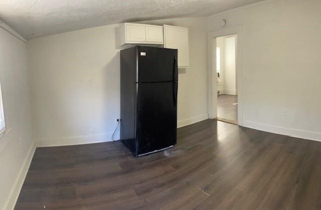 kitchen with white cabinets, dark hardwood / wood-style floors, black fridge, and a textured ceiling