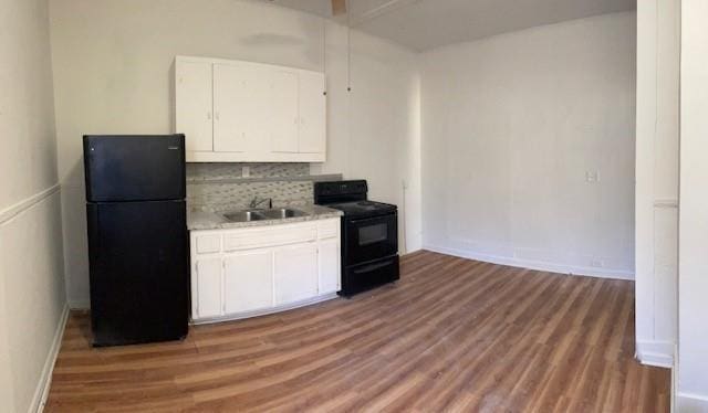 kitchen with dark wood-type flooring, black appliances, sink, decorative backsplash, and white cabinetry