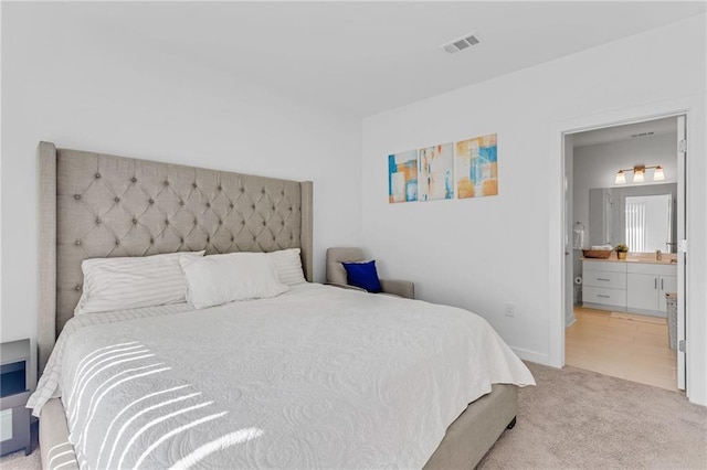 bedroom with sink, ensuite bath, and light carpet