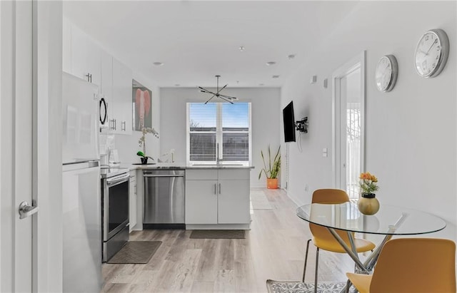 kitchen featuring white cabinets, light hardwood / wood-style floors, and appliances with stainless steel finishes