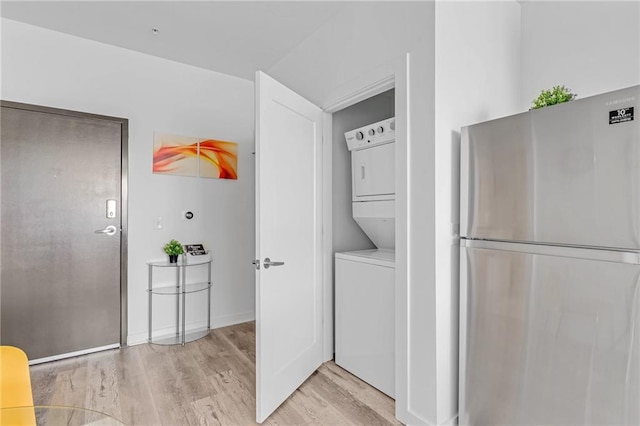 clothes washing area featuring stacked washer and clothes dryer and light hardwood / wood-style floors