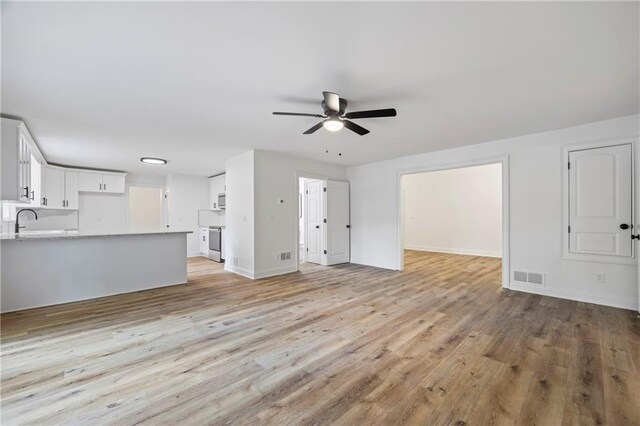 unfurnished living room with sink, light hardwood / wood-style flooring, and ceiling fan