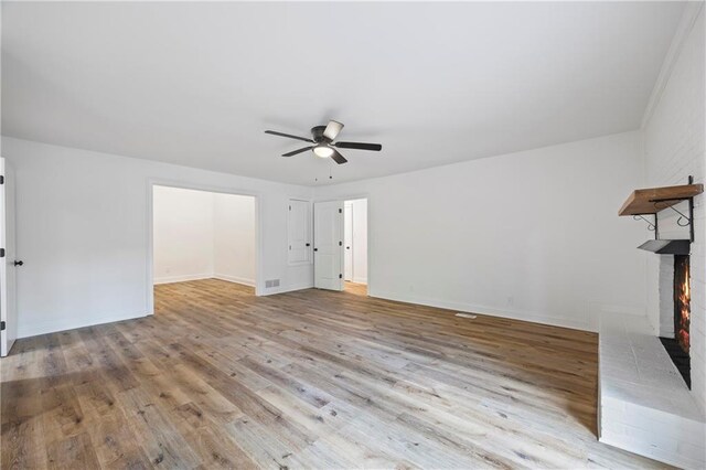 unfurnished living room featuring a fireplace, ceiling fan, and light hardwood / wood-style floors