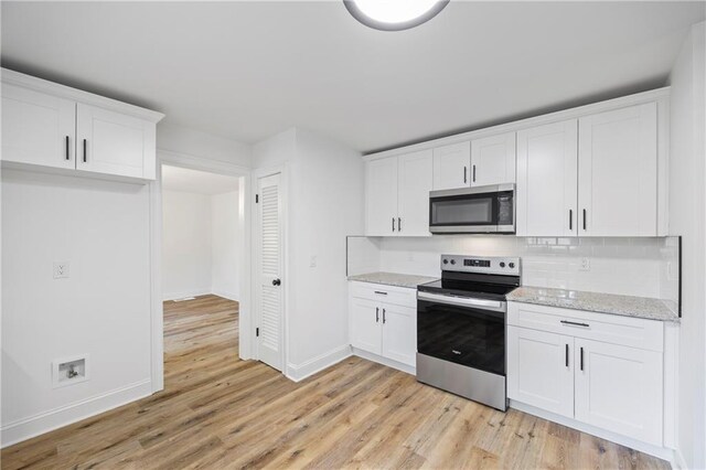 kitchen with white cabinetry, stainless steel appliances, decorative backsplash, and light wood-type flooring