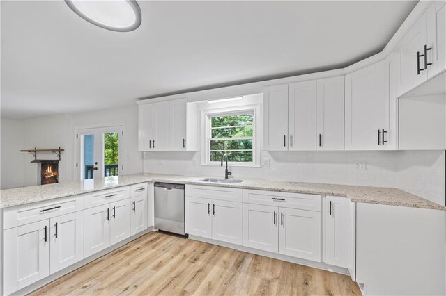 kitchen with sink, stainless steel dishwasher, white cabinetry, and light wood-type flooring