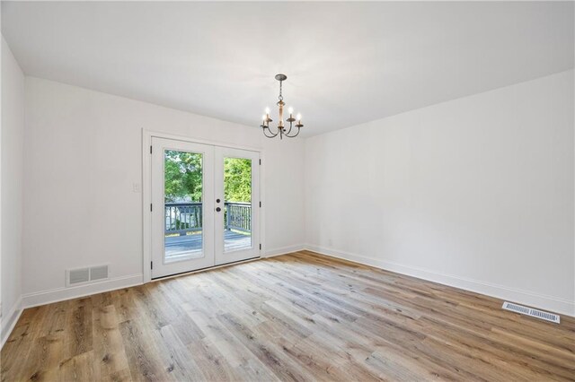 empty room featuring an inviting chandelier, french doors, and hardwood / wood-style floors