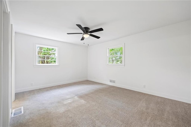 empty room featuring ceiling fan, light carpet, and plenty of natural light