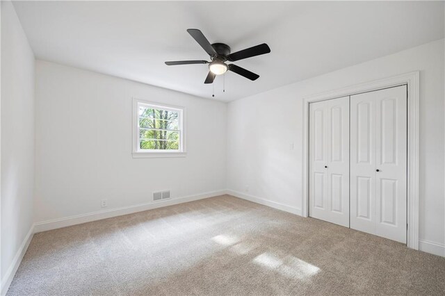 unfurnished bedroom with light carpet, a closet, and ceiling fan