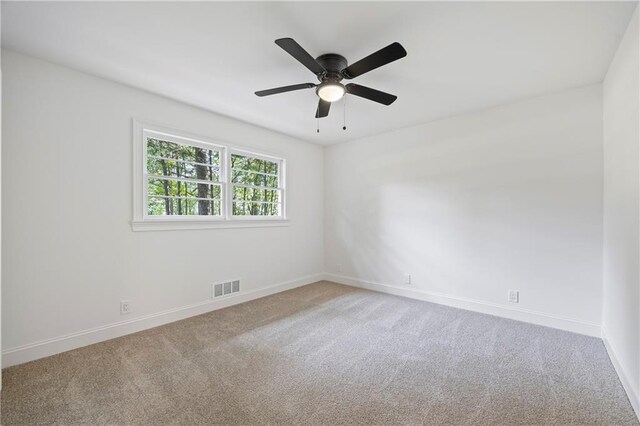 spare room featuring light colored carpet and ceiling fan