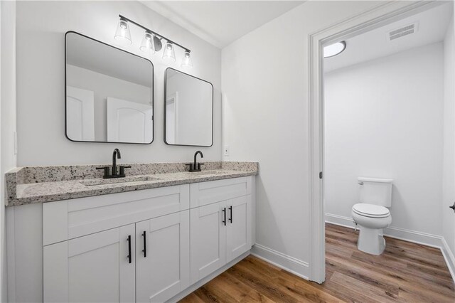 bathroom featuring toilet, double sink vanity, and hardwood / wood-style floors