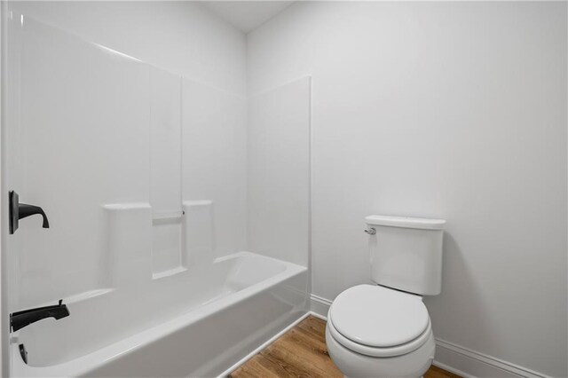 bathroom with tub / shower combination, toilet, and hardwood / wood-style flooring