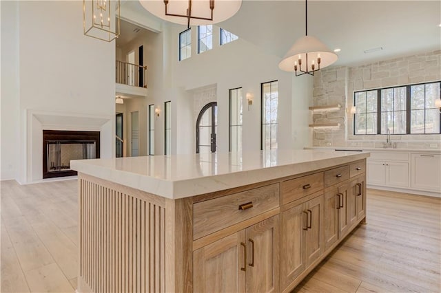 789 Old Mill Ct, Ball Ground, GA 30107 - kitchen with a chandelier, a fireplace, light wood-style flooring, pendant lighting, and a high ceiling