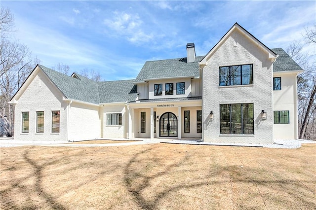 789 Old Mill Ct, Ball Ground, GA 30107 - rear view of house with brick siding, a chimney, a porch, a shingled roof, and a lawn